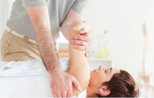Postura de Quiropráctica en medicina alternativa. Mujer y maniobra con el brazo
